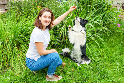 Portrait of young woman with dog on grassy field