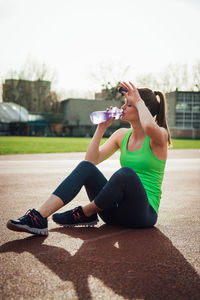 Full length of young woman sitting on bottle