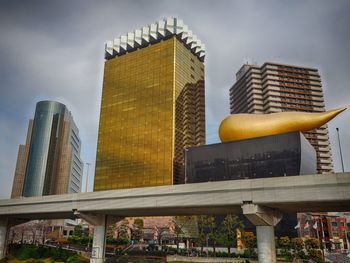 Low angle view of asahi beer hall against sky in city