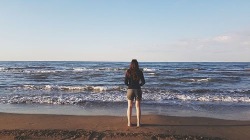 Rear view of woman on beach against sky