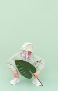 Woman sitting on wall against white background