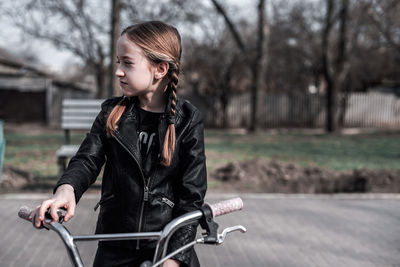 Smiling girl with bicycle at park