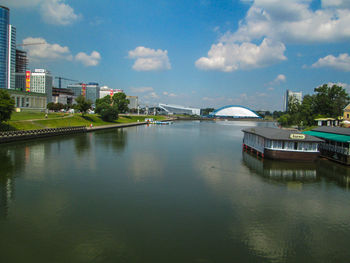 Bridge over river by buildings in city against sky