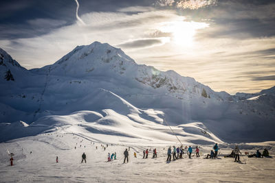 Group of people on snowcapped mountain against sky