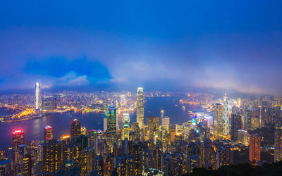 High angle view of illuminated cityscape and river against sky at dusk