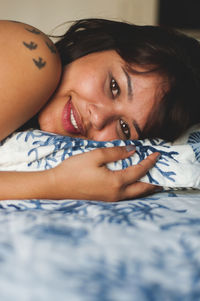 Portrait of young woman lying on bed at home