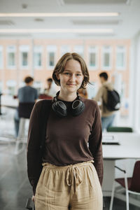 Portrait of smiling female student standing in university