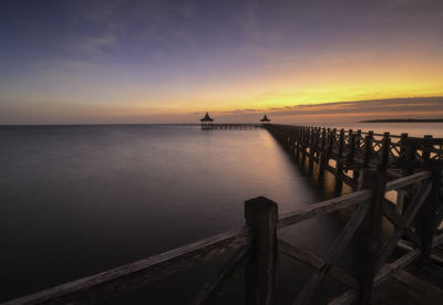 Pier over sea against sky during sunset