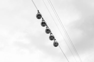 Low angle view of overhead cable cars against sky