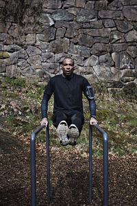 Male athlete exercising on parallel bars in forest