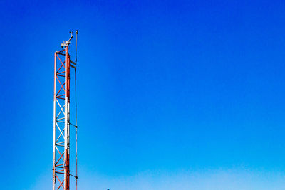 Low angle view of crane against clear blue sky