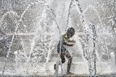 Playful boy enjoying at water fountain