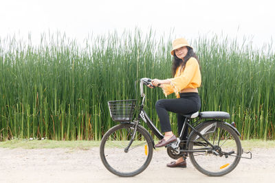 Portrait of woman with bicycle on footpath by plants
