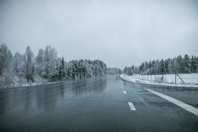 Road amidst trees against sky during winter