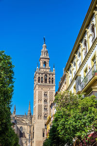 Low angle view of trees and building against sky