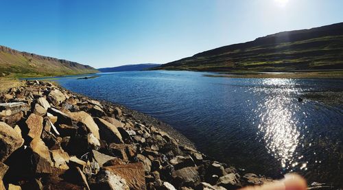 Scenic view of river amidst mountains against blue sky