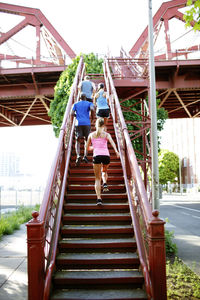 Low angle view of friends running on steps in city