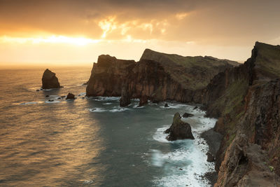 Rocks on sea against sky during sunset