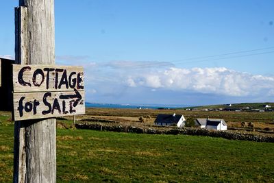 Information sign on wooden post on field against sky