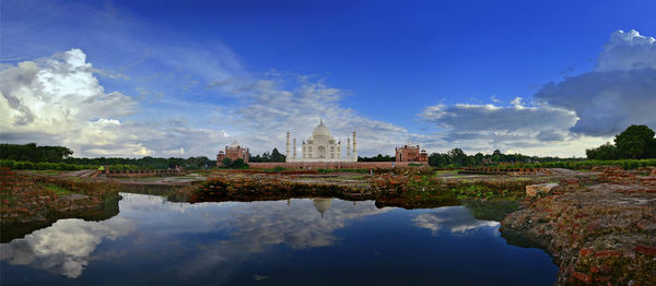 Panoramic view of lake and taj mahal against blue sky