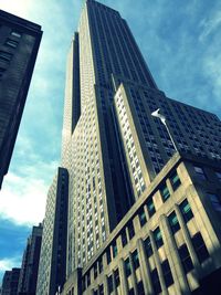 Low angle view of skyscrapers against cloudy sky