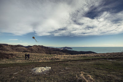 Person on field by sea against sky