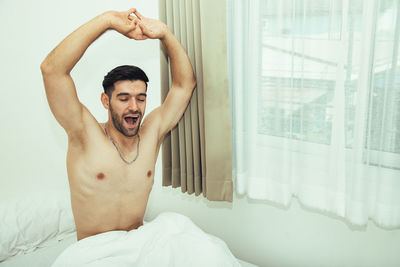 Portrait of shirtless young man lying on bed