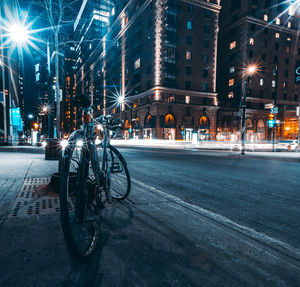Bicycles on city street by buildings at night