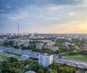 Aerial view of buildings and street against cloudy sky during sunset