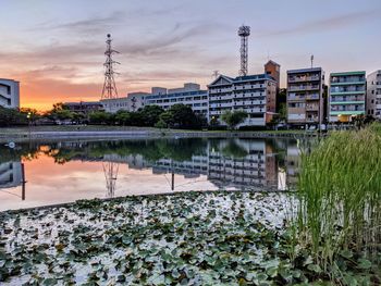 River by buildings against sky during sunset