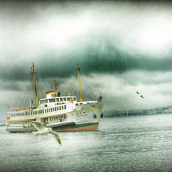 Boats in sea against cloudy sky