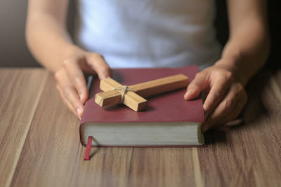 Midsection of woman reading book on table