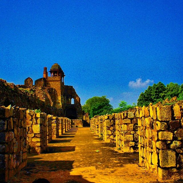 architecture, built structure, building exterior, blue, the way forward, clear sky, house, stone wall, copy space, sky, history, narrow, old, diminishing perspective, wall - building feature, walkway, sunlight, residential structure, day, pathway