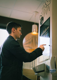 A young man makes an order for fast food on a scoreboard screen in a diner.