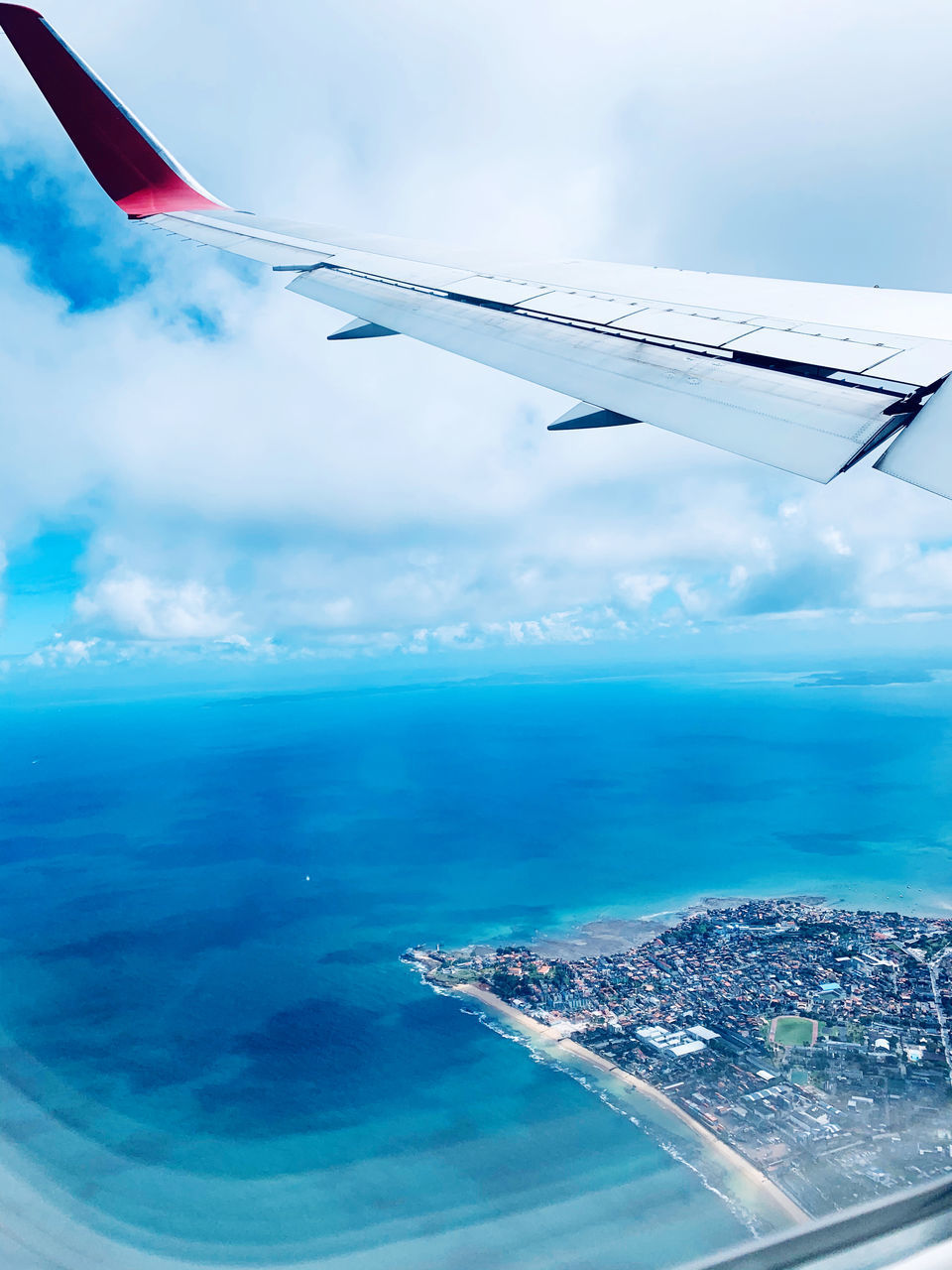 AERIAL VIEW OF SEA AND AIRPLANE FLYING OVER CLOUDS