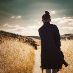 Rear view of woman standing on field against sky
