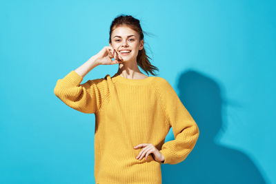 Portrait of smiling young woman against blue background