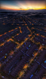 High angle view of illuminated city buildings against sky at sunset