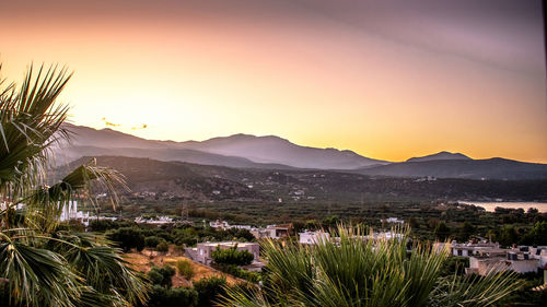 Scenic view of townscape and mountains against sky at sunset