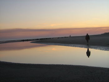 Silhouette person on beach against sky during sunset