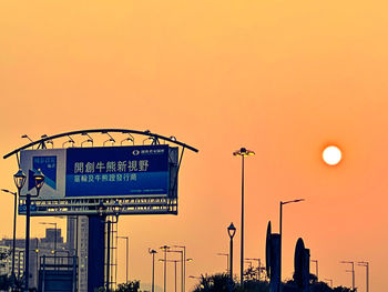 Low angle view of street lights against orange sky