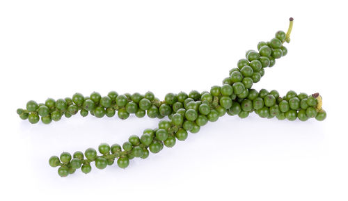 Close-up of raw black peppercorns over white background