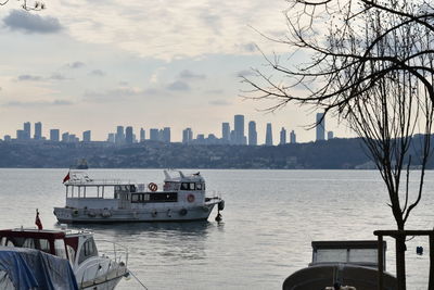 Boats in sea by buildings against sky in city