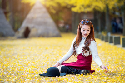 Portrait of young woman sitting on autumn leaves