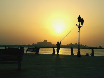 Man on river against sky during sunset