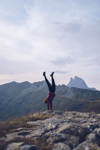 Young man doing handstand on mountain around ibones of anayet