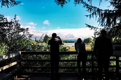 Rear view of silhouette people standing against railing