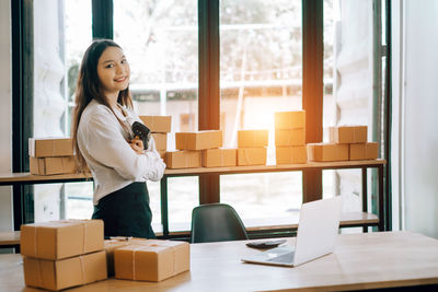 Young woman using phone while standing on table