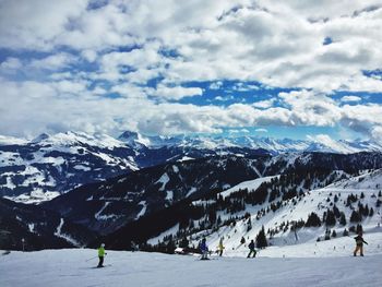 People skiing on snow against mountains