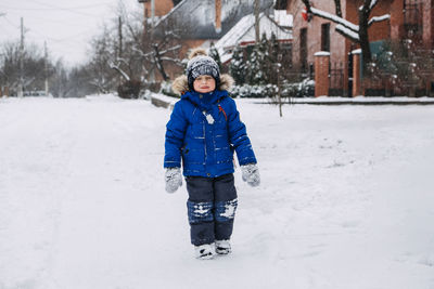 Best outdoor winter activities for kids. cute kid boy in blue winter jacket playing snowballs on